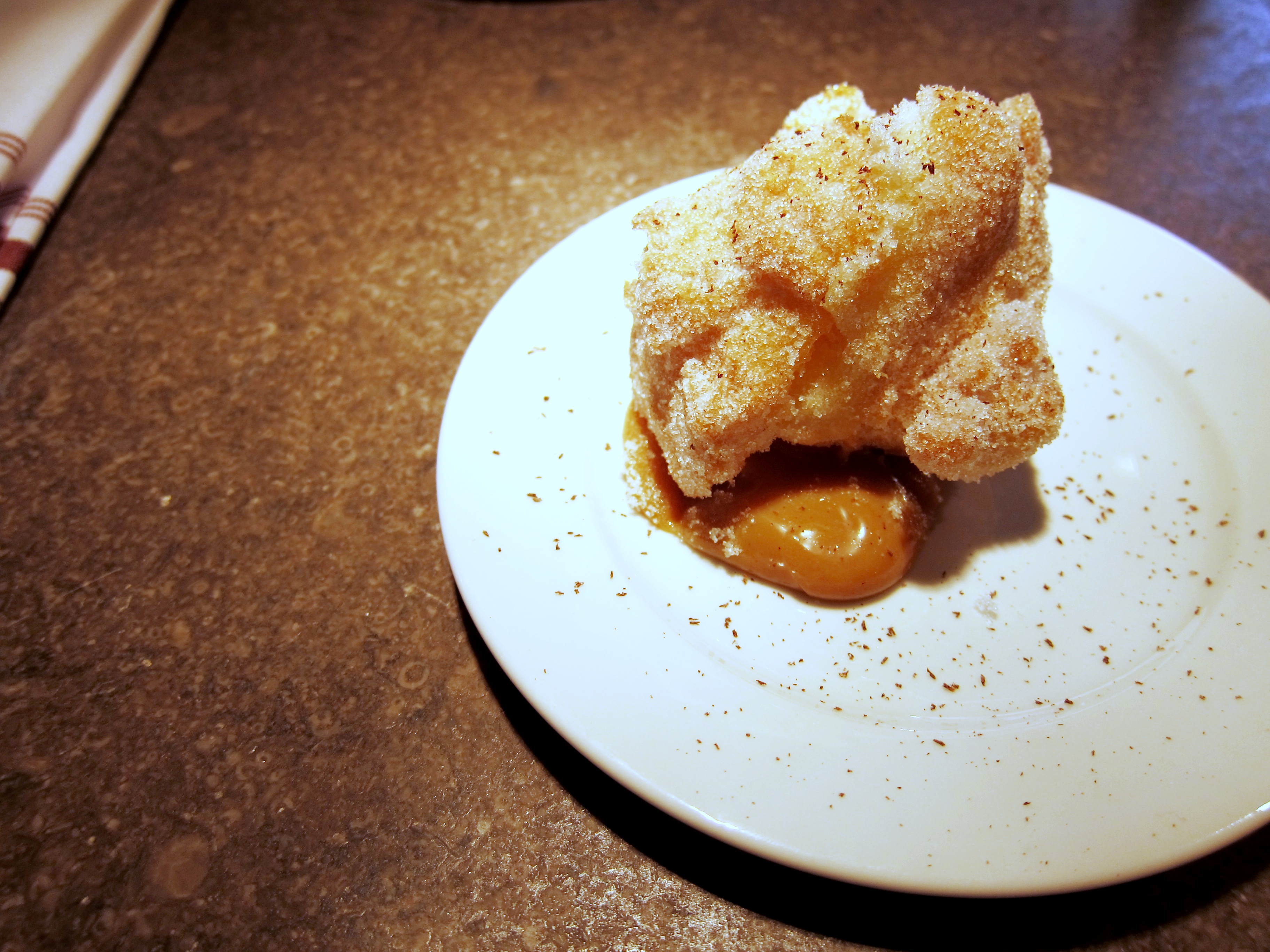 Doughnut sprinkled with cocoa shavings and sugar, served with butter caramel